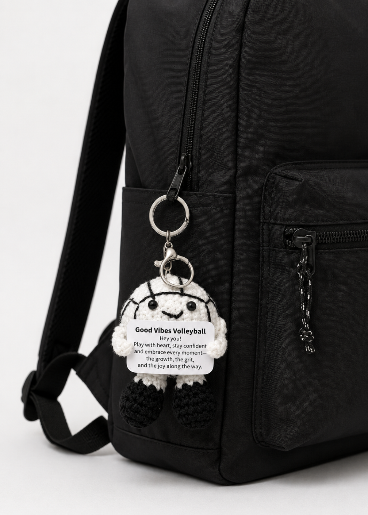 Black backpack with a keychain featuring a volleyball character and text on a white background
