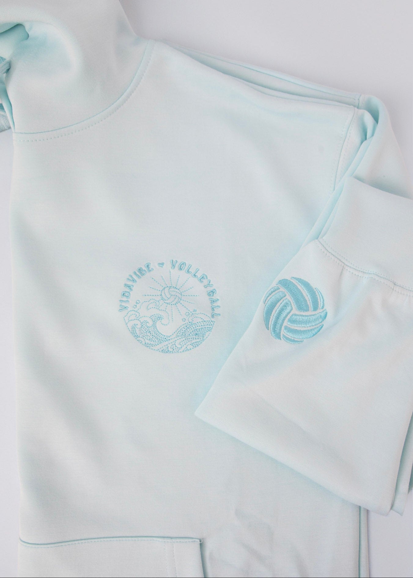 Baby blue sweatshirt with volleyball and waves on the front, volleyball embroidered on the sleeve