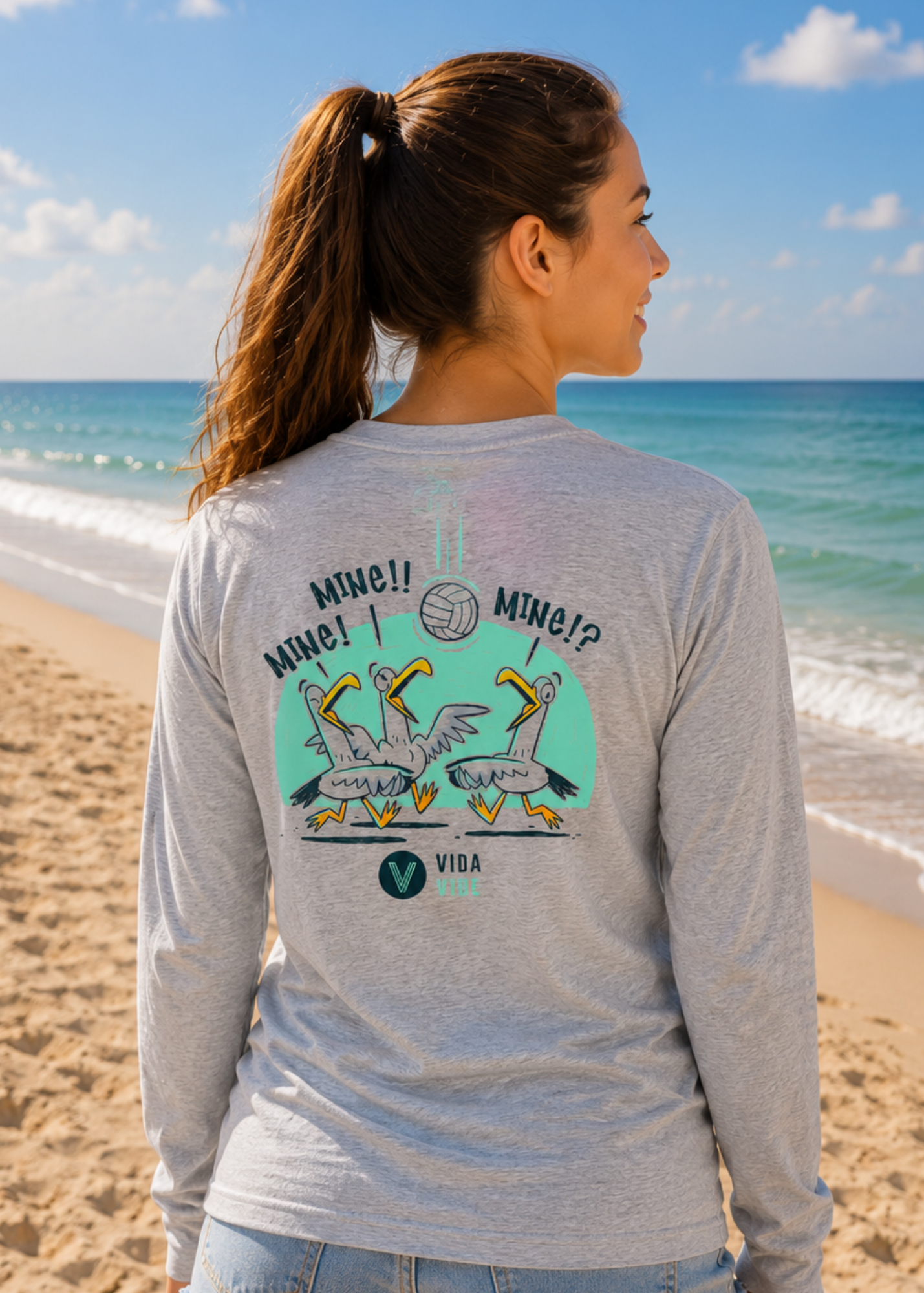 Woman wearing a gray long-sleeve volleyball shirt with a graphic design on the beach