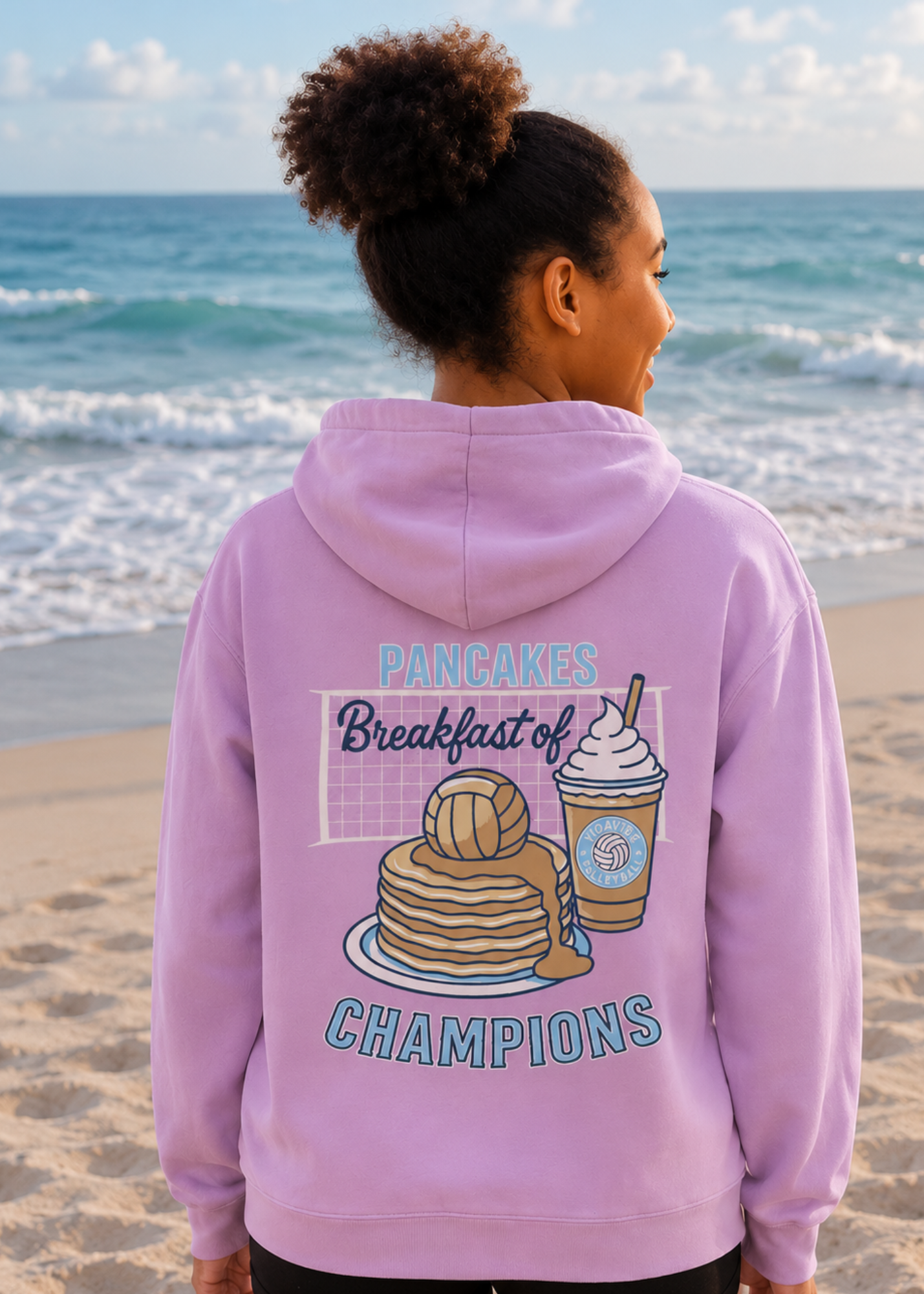 Person wearing a pink hoodie with a graphic volleyball design on the beach