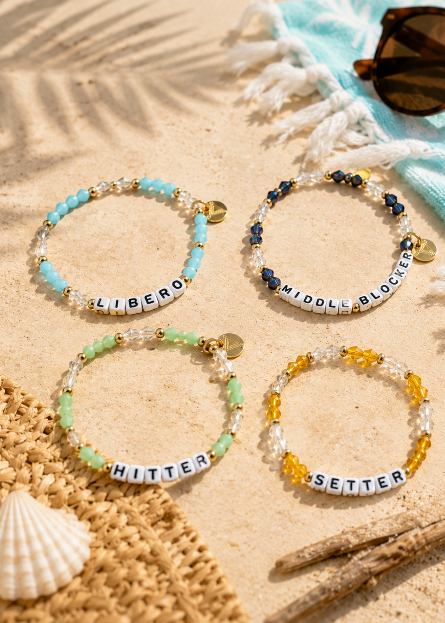 Four beaded volleyball bracelets with word charms on a sandy background