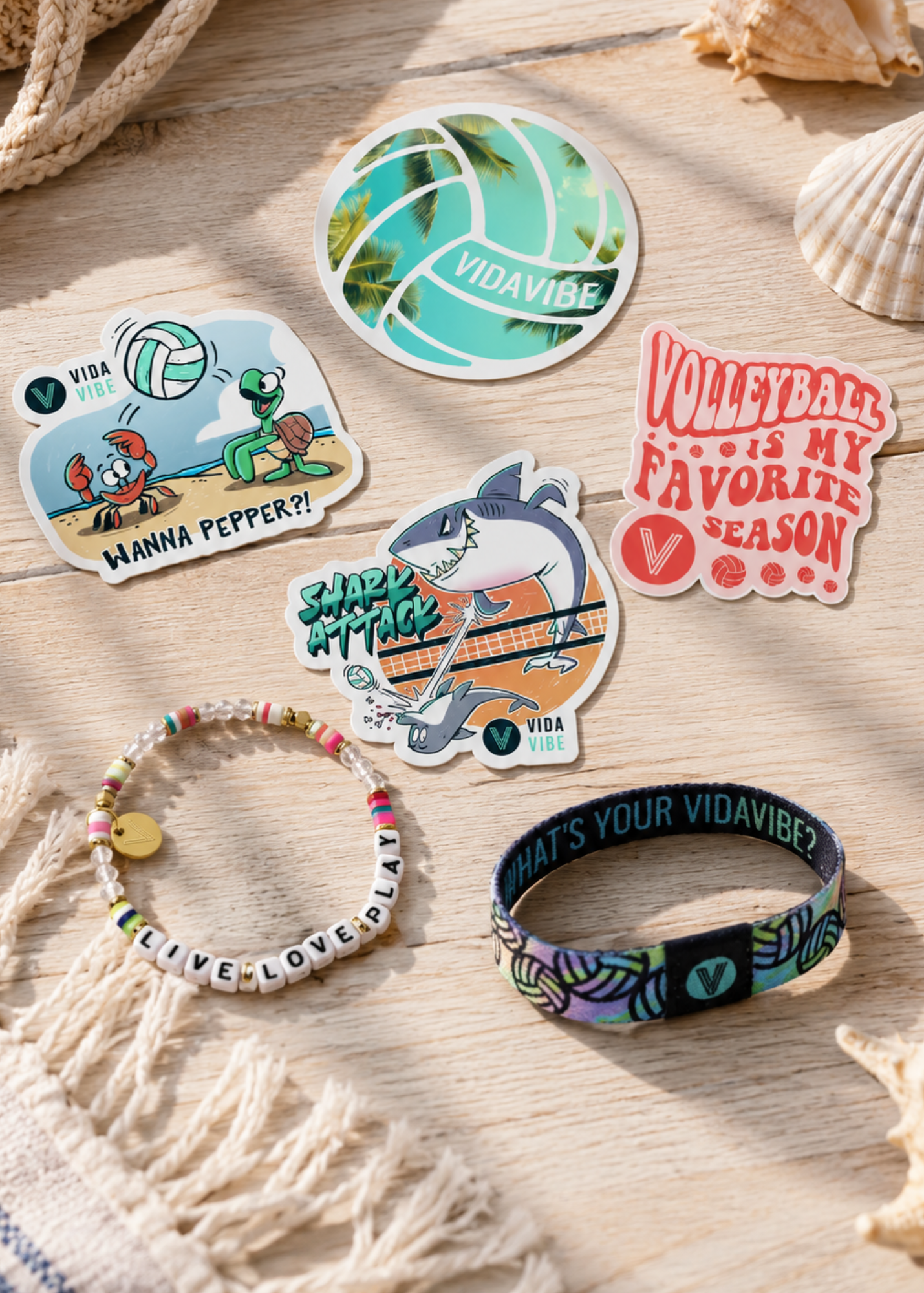 Collection of Vidavide Volleyball stickers and accessories on a wooden surface with seashells.